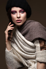 Beautiful sexy long-haired brunette woman in knitted clothes posing in the studio. The beauty of the face and body. Photos shot in a studio