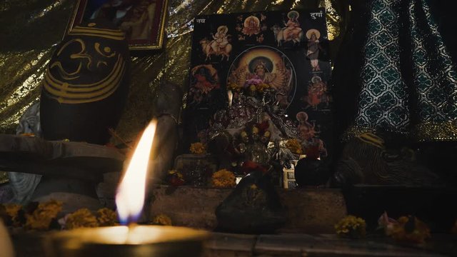 A candle burning in front of the image of Goddess Kali in indian ashram