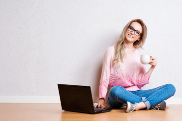 Young creative woman sitting in the floor with laptop. Casual bl