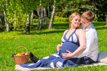 loving young couple expecting a baby, rest on a picnic in the pa