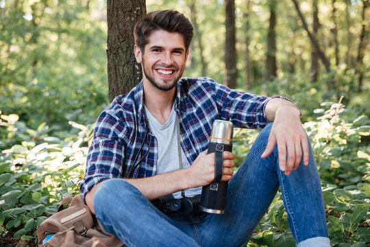 Guy sitting with thermos in forest