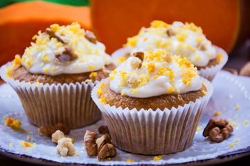 pumpkin cupcakes with cream and pumpkin on a table