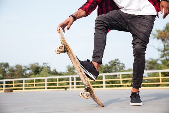 Cropped photo of young dark skinned man skateboarding