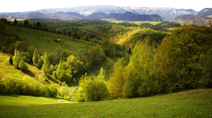 View across hills and farmland to the mountains of the Piatra Craiului National Park, Romania.