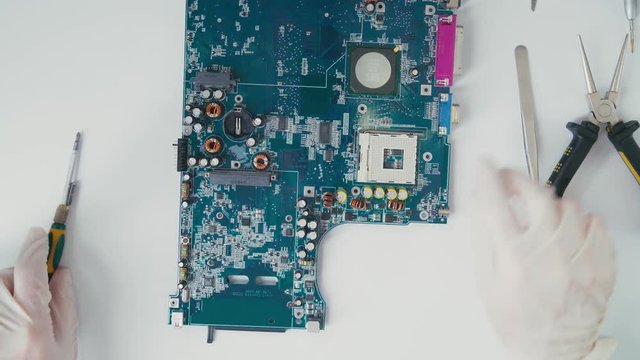 Passive Components PCB micro: resistors and capacitors. Master electrician working with the circuit board. Collection of elements of the PCB with the chip. Tools for repairing electronic circuit board