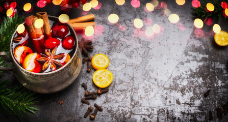 Banner with mulled wine cup and spices on dark rustic background with bokeh