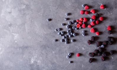 Raspberries, blackberries, blueberries a gray abstract background. Copyspace. Healthy food concept. Colorful festive still life. Loosely laid berries in different positions