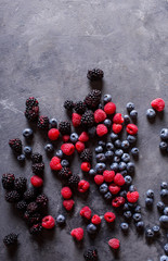 Raspberries, blackberries, blueberries a gray abstract background. Copyspace. Healthy food concept. Colorful festive still life. Loosely laid berries in different positions