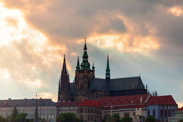 Panoramic view of St. Vitus Cathedral and Castle in Prague, Czech Republic. Beautiful dramatic sunset sky with rays of making their way through clouds.