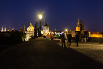 Prague, Czech Republic. Charles Bridge with its statuette at night, Old Town Bridge Tower in the background.
