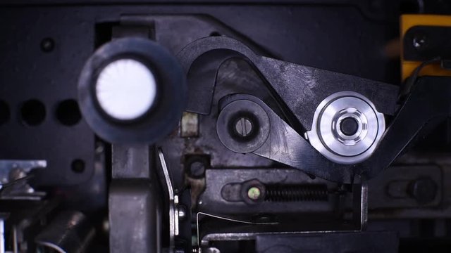 Vintage old movie projector, feed sprocket detail while film is running