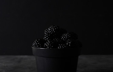 Blackberry. Blackberries  in black decorative vase on a dark abstract background. Copyspace. Healthy food concept.  Colorful festive still life. Fresh berries. Art food photography. Dark light