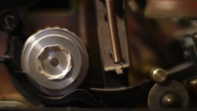 Vintage old movie projector, takeup sprocket and sound head detail while film is running