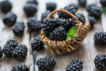 Close-up of ripe blackberries in a tiny basket between dispersed