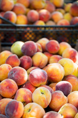 Fresh organic juicy peaches in black plastic boxes at market