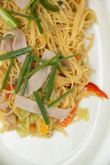  stir fried yellow noodles with ham and vegetable on white dish