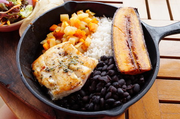 Traditional Costa Rican Casado meal with rice, beans, plantains and fish