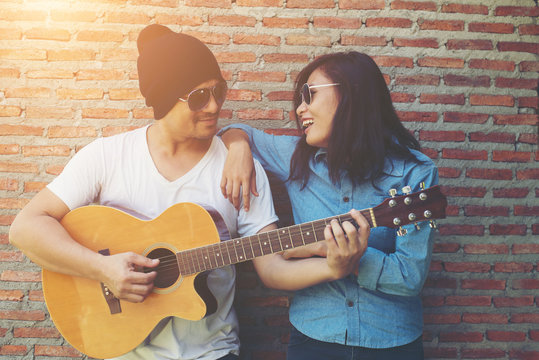 Hipster couple is hugging, looking away and smiling while standi