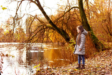 Little girl walking on the lake shore to enjoy the autumn landsc