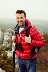 Happy man standing with backpack during autumnt hike