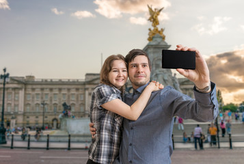 Young happy couple is taking selfie photo near Buckingham palace.