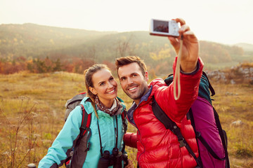 Happy couple taking selfie during autumn, fall hiking adventure