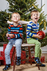 Two little smiling kids, boys keep balls on Christmas tree background. Happy friendly children. Selective focus