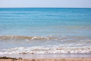 Fototapeta na wymiar Small wave on seashore. Sea with blue sky. Good spot for summer vacation. Swim and sunbathe.