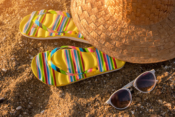 Flip flops and beach hat. Sunglasses on sand background. Warm exotic resort. Summer is calling you.
