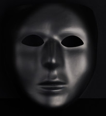 Anonymous black mask protruding from pitch black background. Anonymity concept
