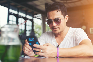 Happy young man looking at his mobile phone and smiling while si