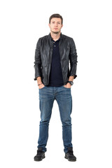 Naklejka premium Confident young casual man in leather jacket and jeans with hands in pockets. Full body length portrait isolated over white studio background.