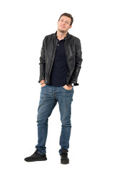 Fototapeta premium Young casual man in leather jacket and blue jeans with smirk smile tilting head. Full body length portrait isolated over white studio background.