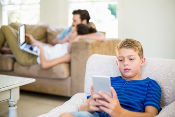 Fototapeta premium Boy sitting on sofa and using mobile phone