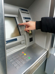 Man's using the ATM machine with cash cards. Close-up of hand entering PIN/pass code on ATM/bank...