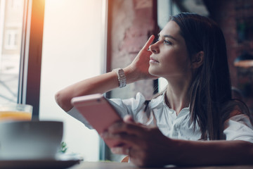 Handsome woman sitting in cafe and using mobile phone to text in social network messengers
