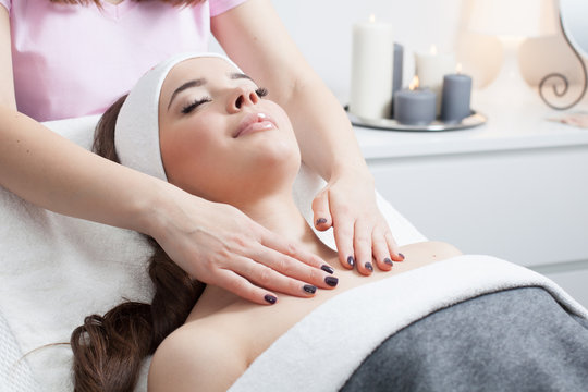 Beautiful young woman receiving facial massage with closed eyes in a spa salon 