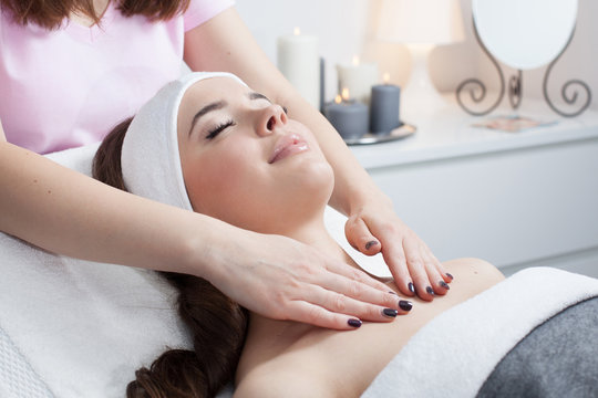 Beautiful young woman receiving facial massage with closed eyes in a spa salon 