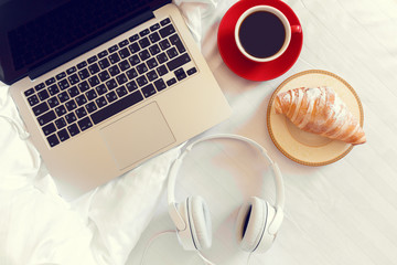 Morning background. Coffee with bun and laptop in bed
