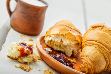 Croissant with fruit jam and fresh milk for breakfast. Delicious French meal on a table.