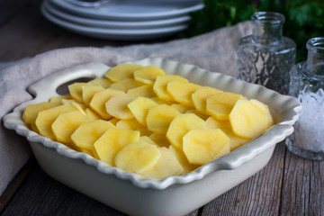 Raw potato gratin in the cooking process, horizontal