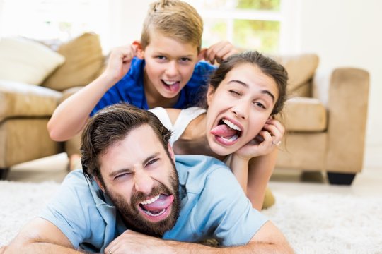 Portrait Of Parents And Son Lying On Rug And Having Fun