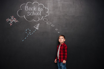 Boy over chalkboard with school drawings while looking on it