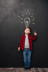 Little boy pointing up and having idea over chalkboard background