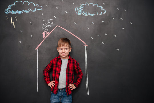 Kid standing in house on chalkboard with drawings of rain
