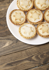 A plate full of freshly baked mince pies on a rustic wooden dining table background with empty space below
