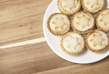 A plate full of freshly baked fruit pies on a wooden kitchen counter background with blank space at side
