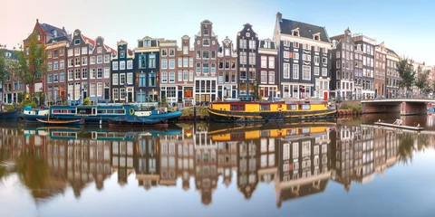 Poster Panorama van het Amsterdamse kanaal Singel met typisch Nederlandse huizen, brug en woonboten tijdens het ochtendblauwe uur, Holland, Nederland. © Kavalenkava