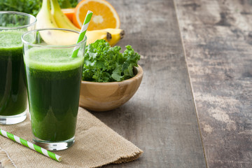 Kale smoothie with banana and orange on wooden background
