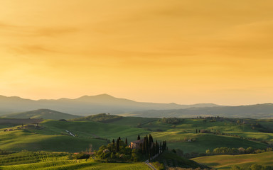Farmhouse, green hills,cypress trees in Tuscany at sunrise in Italy